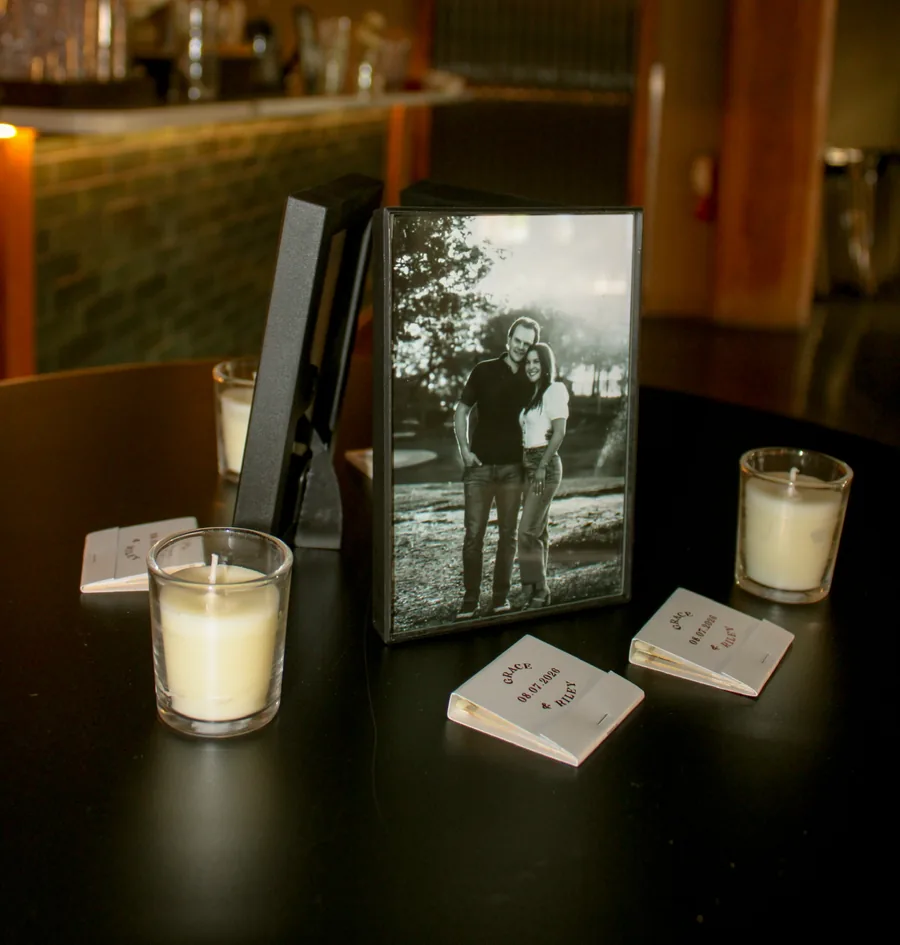 Candles, matchbooks and a framed black and white photograph on a dark bar table