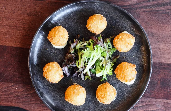 Panko-crusted arancini plated with dressed greens