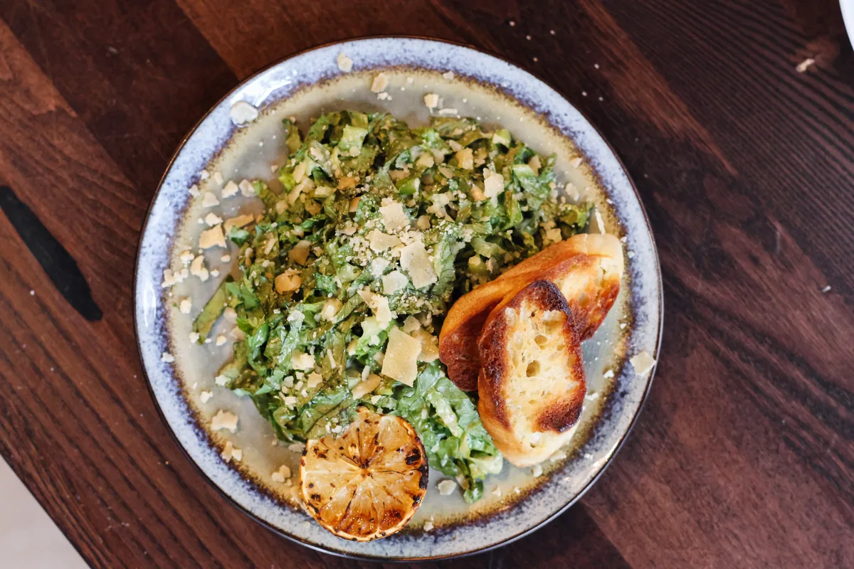 A Caesar salad with croutons on a white plate