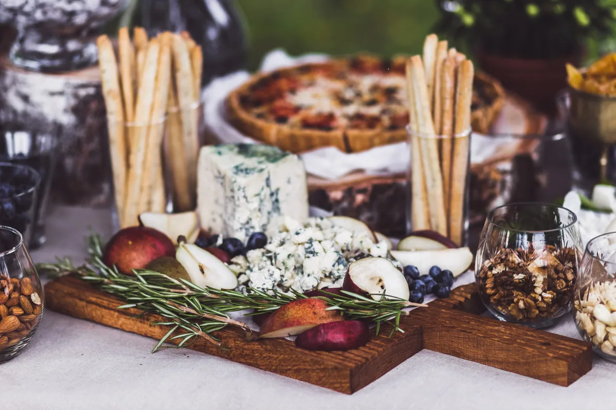 A grazing board of cheeses, pears, walnuts and breadsticks