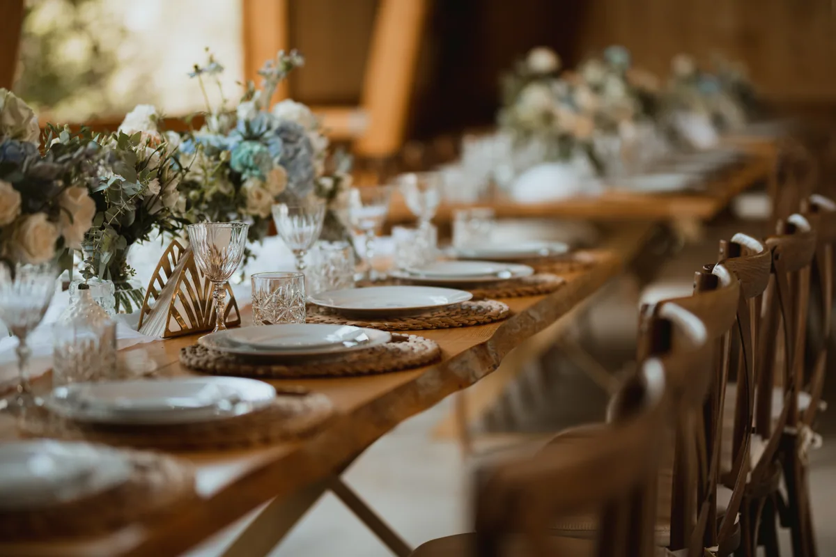 A long wedding table set with plates, cut glass and blue and white flowers