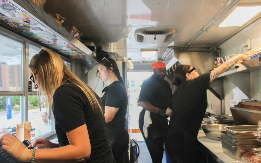 Four cooks working the line inside the Cream City food truck during a lunch service