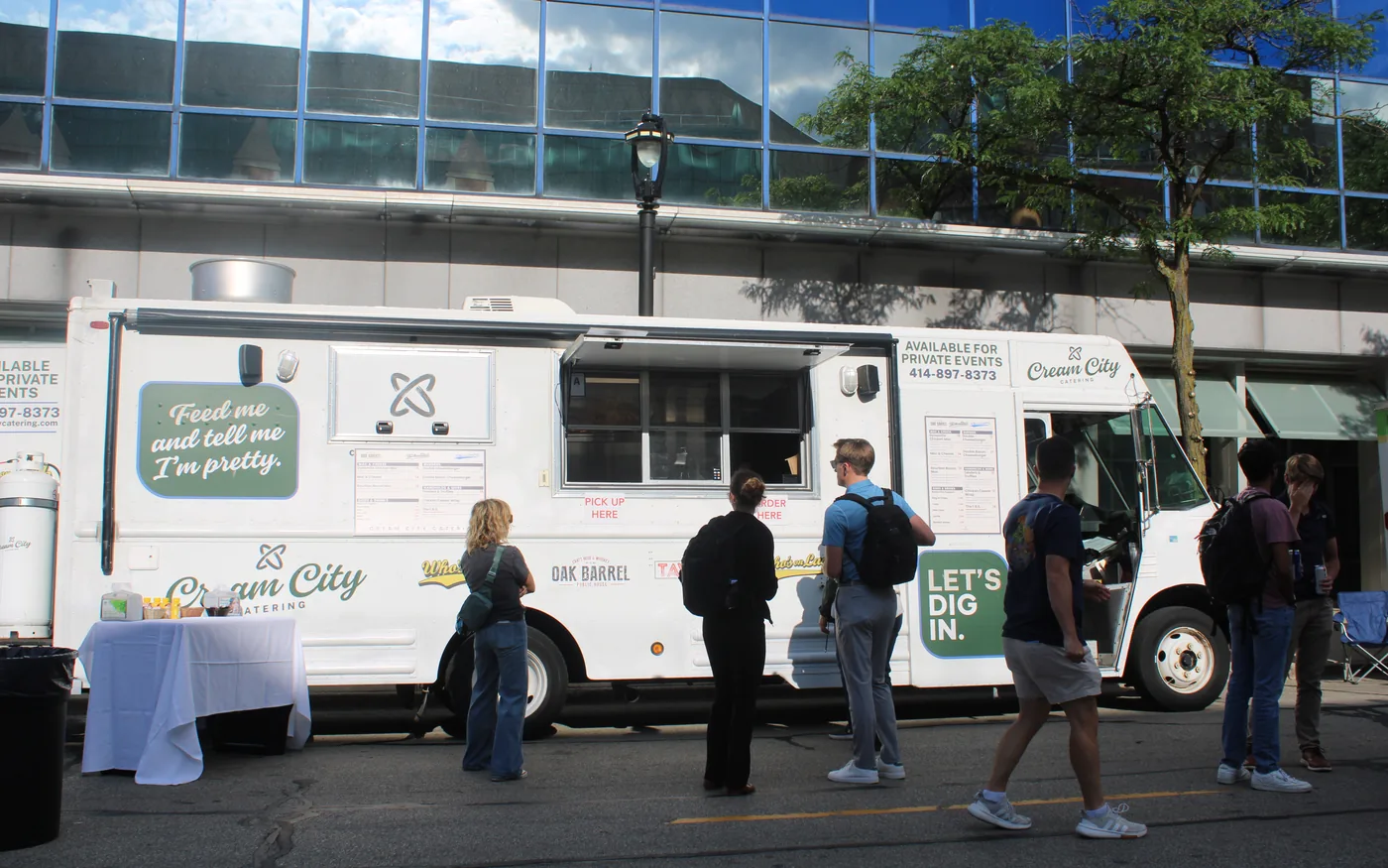 The Cream City Catering food truck parked on a downtown Milwaukee street with a queue of people waiting to order